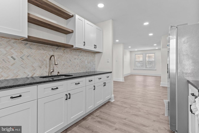 kitchen with light wood finished floors, open shelves, freestanding refrigerator, a sink, and white cabinets