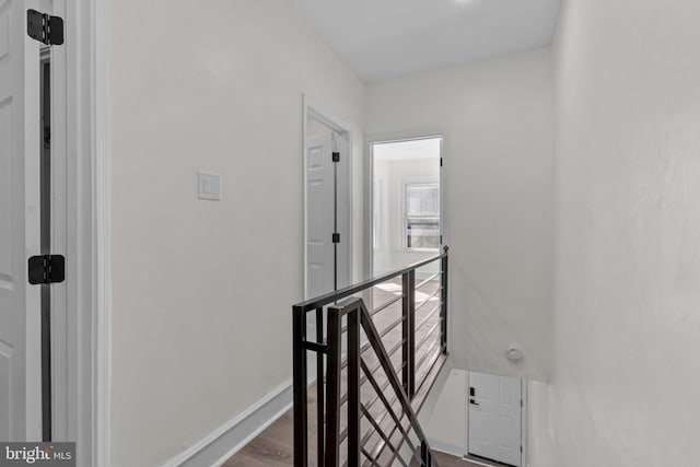 corridor featuring baseboards, an upstairs landing, and dark wood-style floors