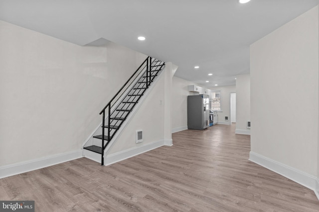 unfurnished living room featuring stairs, baseboards, visible vents, and light wood-type flooring