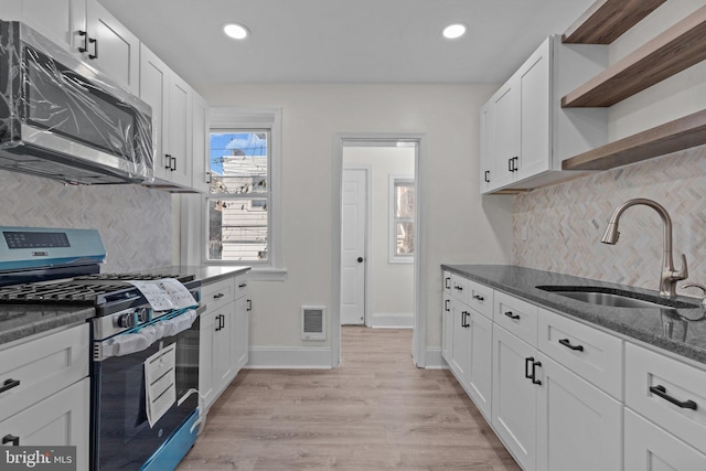 kitchen featuring visible vents, light wood finished floors, open shelves, a sink, and stainless steel appliances