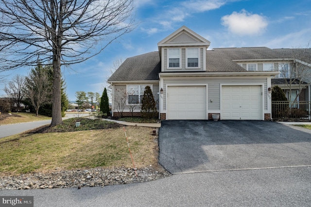 traditional home featuring aphalt driveway, a front lawn, and a shingled roof