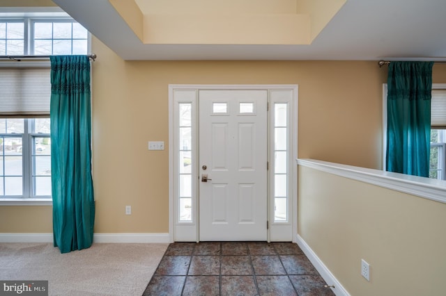 carpeted foyer entrance featuring a wealth of natural light and baseboards