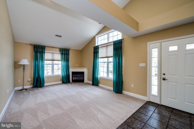 entryway featuring visible vents, lofted ceiling, carpet floors, a fireplace, and baseboards