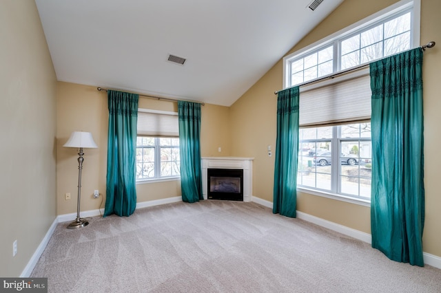 unfurnished living room featuring visible vents, a glass covered fireplace, baseboards, carpet, and lofted ceiling