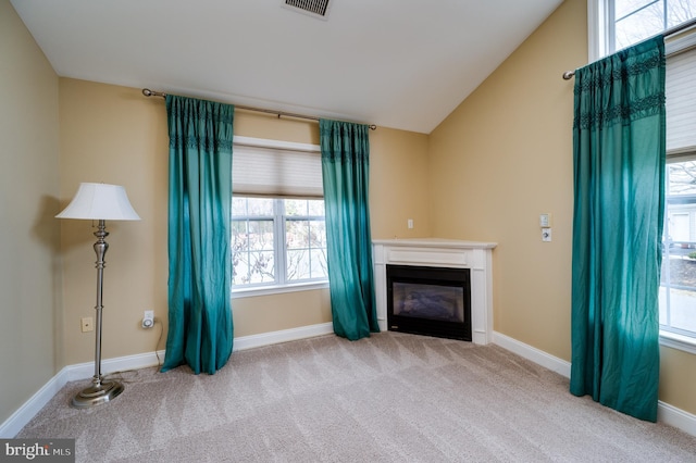 unfurnished living room with a glass covered fireplace, vaulted ceiling, baseboards, and carpet floors