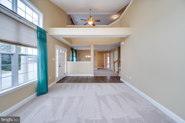 foyer entrance featuring ceiling fan with notable chandelier, stairway, carpet floors, baseboards, and a towering ceiling