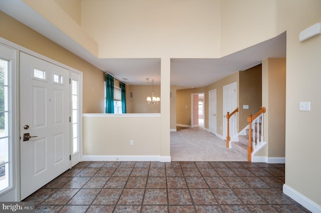 entryway with stairs, baseboards, a chandelier, and a towering ceiling