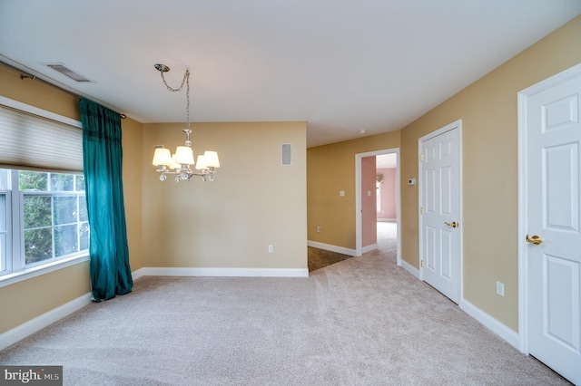 carpeted empty room with a chandelier, visible vents, and baseboards