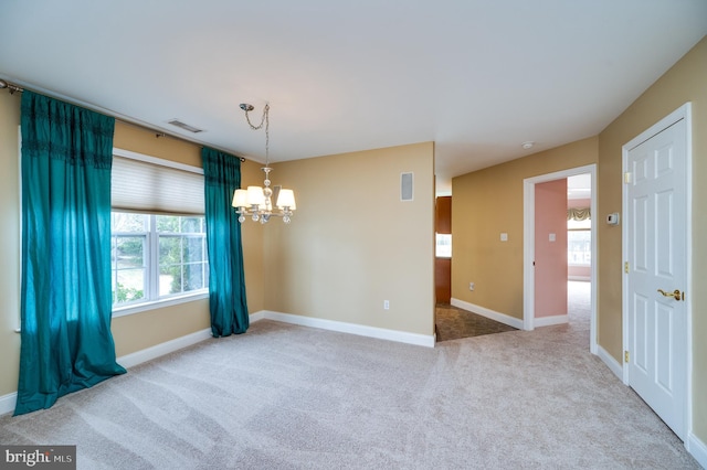 carpeted empty room featuring a wealth of natural light, a notable chandelier, visible vents, and baseboards