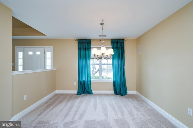 spare room featuring a notable chandelier, visible vents, baseboards, and carpet floors