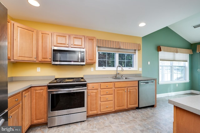 kitchen featuring a sink, vaulted ceiling, light countertops, and stainless steel appliances