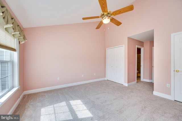 unfurnished bedroom with carpet flooring, multiple windows, high vaulted ceiling, and baseboards