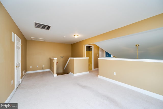 spare room with visible vents, light carpet, baseboards, and attic access