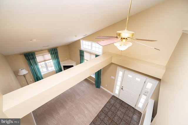 carpeted entrance foyer featuring stone finish flooring, baseboards, and high vaulted ceiling