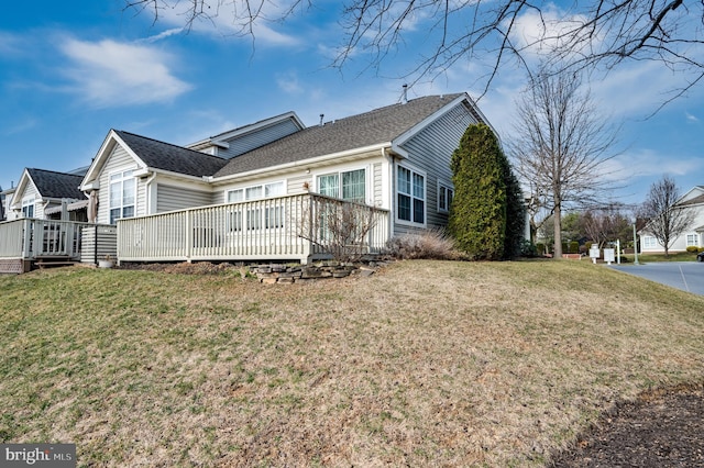 exterior space with a deck, a shingled roof, and a yard