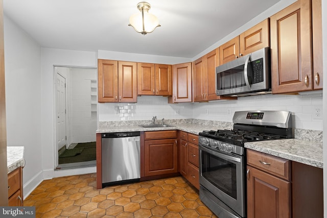 kitchen featuring a sink, decorative backsplash, appliances with stainless steel finishes, and light countertops