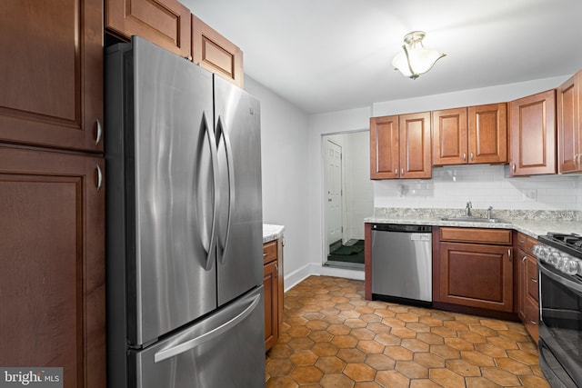 kitchen featuring light stone countertops, a sink, appliances with stainless steel finishes, tasteful backsplash, and brown cabinets