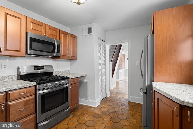 kitchen featuring stainless steel appliances, tasteful backsplash, visible vents, and light countertops