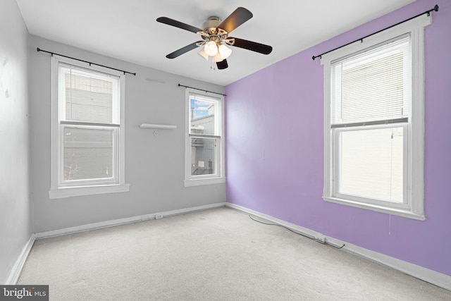 carpeted spare room with a ceiling fan and baseboards