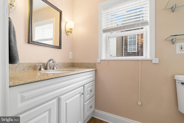 bathroom featuring toilet, vanity, and baseboards