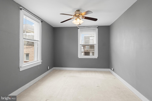 spare room with a ceiling fan, baseboards, and light carpet