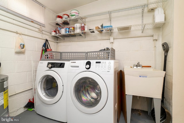 laundry area featuring laundry area, washer and dryer, concrete block wall, and a sink