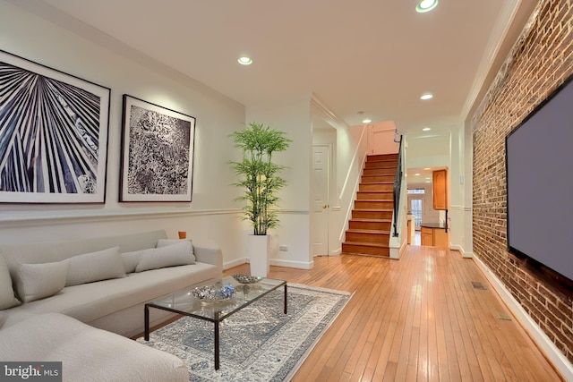 living room with stairway, light wood-style flooring, recessed lighting, and brick wall