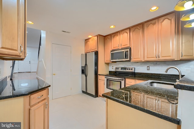 kitchen with backsplash, recessed lighting, dark stone countertops, appliances with stainless steel finishes, and a sink