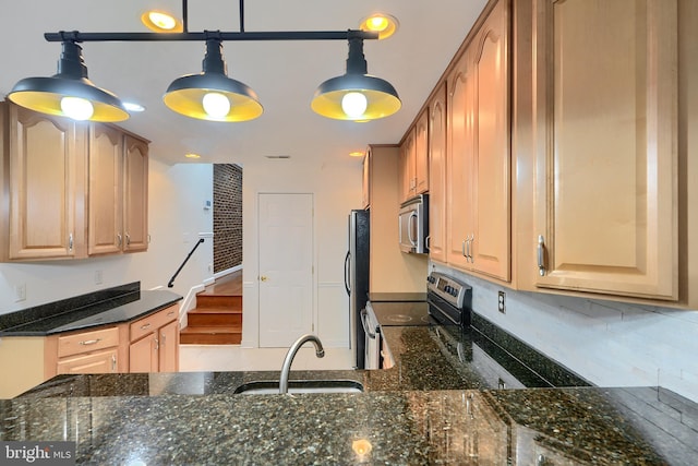 kitchen with dark stone counters, a sink, stainless steel appliances, pendant lighting, and backsplash