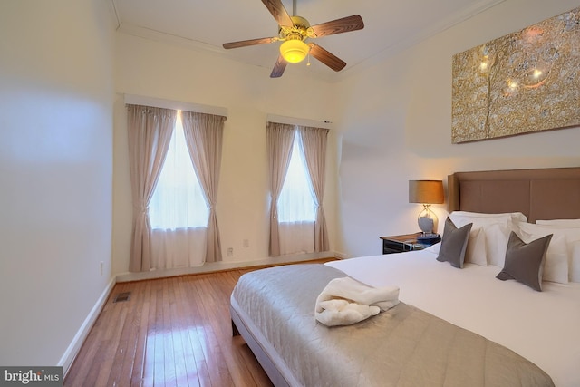 bedroom featuring hardwood / wood-style floors, visible vents, baseboards, ceiling fan, and ornamental molding