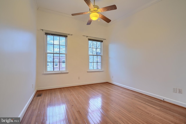 spare room with ceiling fan, baseboards, light wood-style floors, and ornamental molding