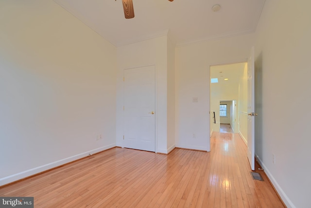 unfurnished bedroom featuring light wood finished floors, visible vents, baseboards, ornamental molding, and a ceiling fan