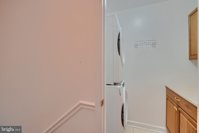 laundry room with cabinet space and stacked washer and clothes dryer