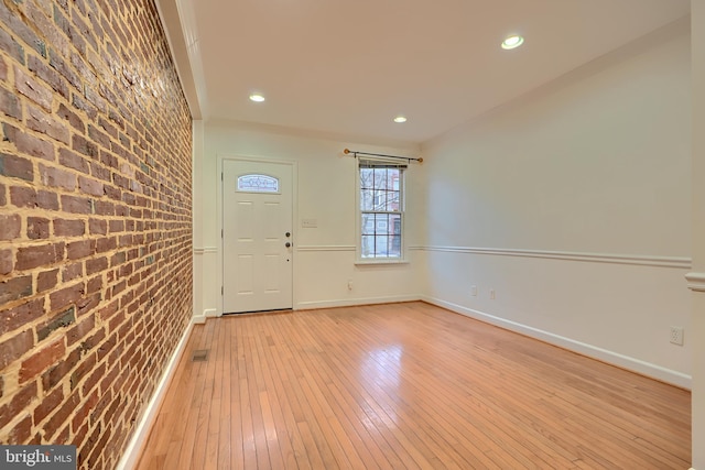 entrance foyer featuring recessed lighting, brick wall, light wood-type flooring, and baseboards