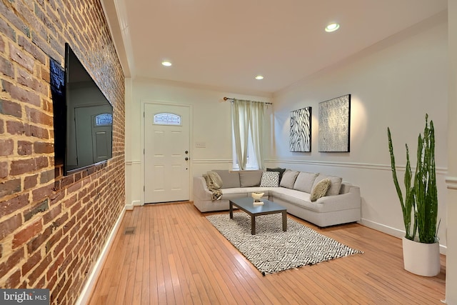 living room featuring recessed lighting, light wood-style floors, baseboards, and brick wall