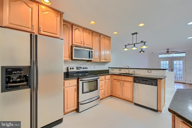 kitchen featuring a sink, backsplash, stainless steel appliances, a peninsula, and hanging light fixtures