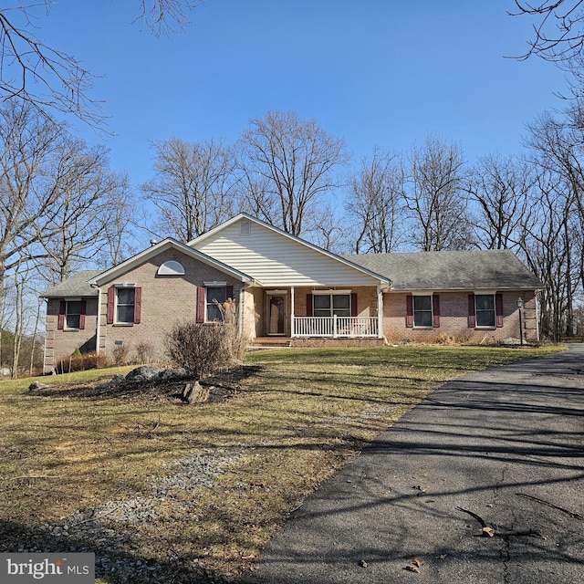 single story home featuring aphalt driveway, brick siding, covered porch, and a front lawn