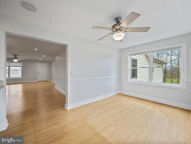 empty room featuring ceiling fan, light wood-type flooring, and baseboards