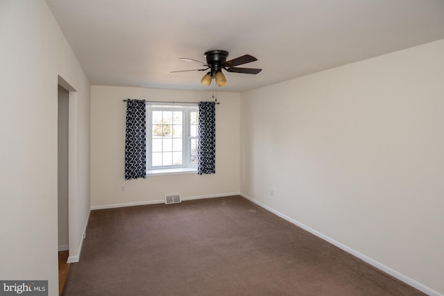 empty room featuring a ceiling fan, baseboards, visible vents, and dark carpet