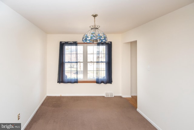 carpeted spare room featuring baseboards and visible vents