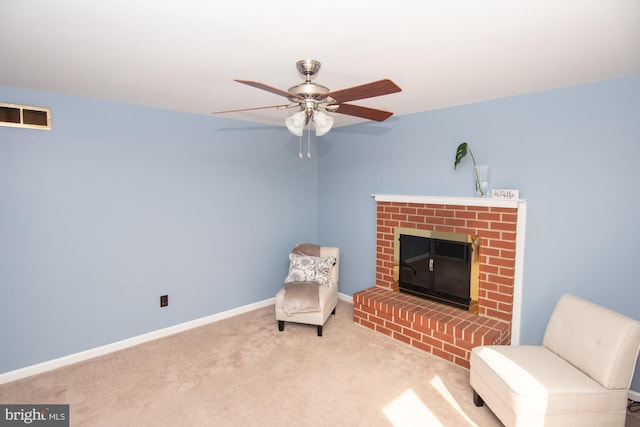 sitting room featuring visible vents, a brick fireplace, baseboards, carpet floors, and a ceiling fan