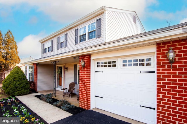 view of front of house with brick siding, covered porch, an attached garage, and driveway