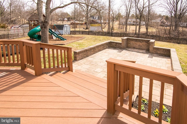 wooden terrace featuring a patio area, a lawn, a playground, and a fenced backyard