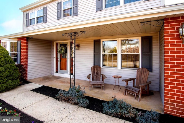 doorway to property with brick siding and covered porch