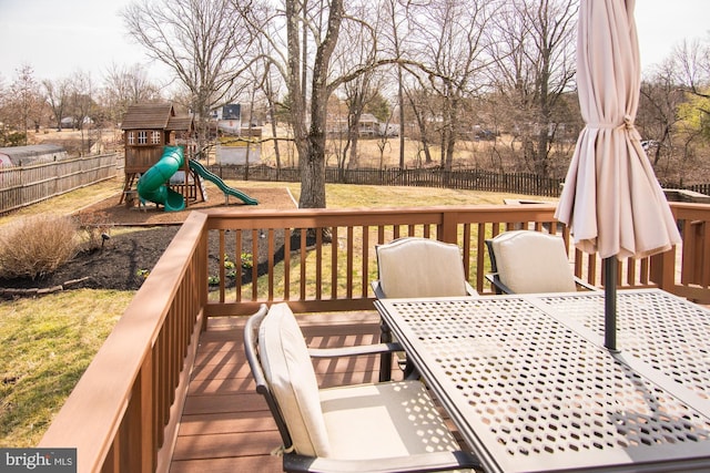 wooden terrace featuring a lawn, a playground, and a fenced backyard