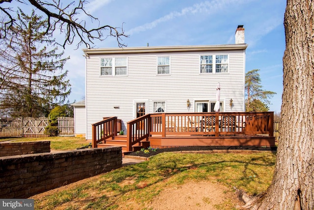 back of house with a wooden deck, a chimney, a yard, and fence