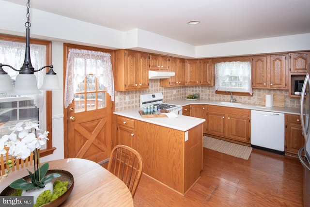 kitchen with decorative backsplash, white appliances, light countertops, and under cabinet range hood