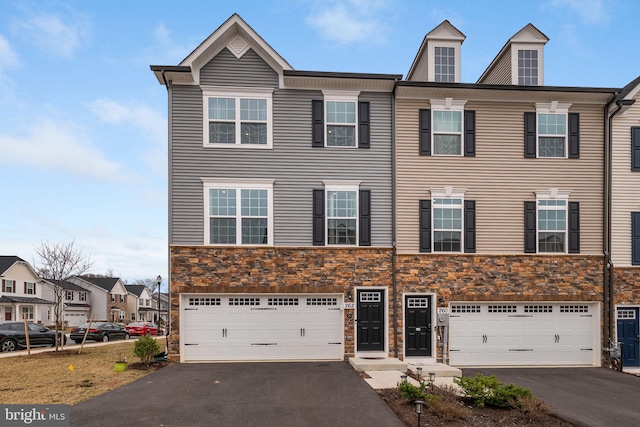 view of property featuring aphalt driveway, an attached garage, stone siding, and a residential view