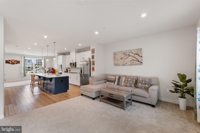 living room with recessed lighting, baseboards, light carpet, and light wood-style floors