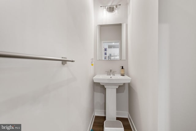 bathroom with a sink, baseboards, and wood finished floors